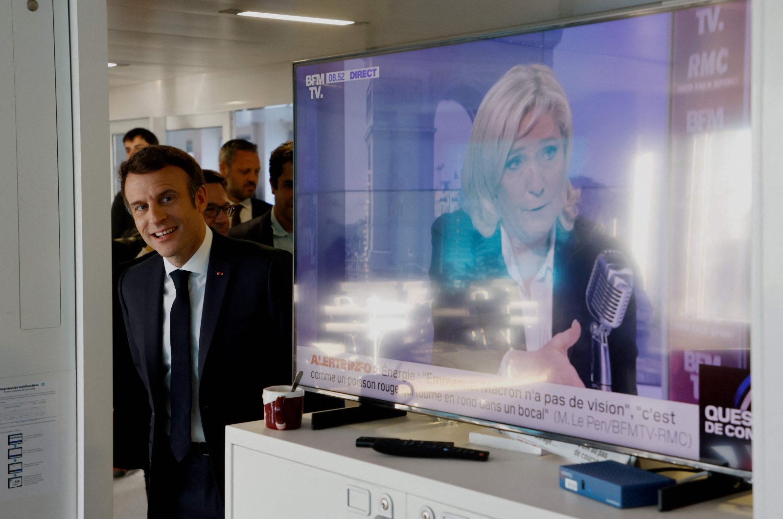 French President Emmanuel Macron visits France Inter&#039;s office, next to a TV screen displaying French far-right party Rassemblement National (RN) presidential candidate Marine Le Pen (R), after the France Inter 7/9 radio broadcast at the Maison de la Radio in Paris, France, April 4, 2022. (AFP Photo)