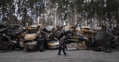 A man walks past a storage place for burned armed vehicles and cars, in the outskirts of Kyiv, Ukraine, April 11, 2022. (AP Photo)