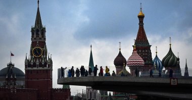 Pedestrians walk on a bridge in the Zaryadye Park, with the Kremlin's Spasskaya tower and St. Basil Cathedral in the background, Moscow, Russia, Nov. 4, 2021. (AFP Photo)