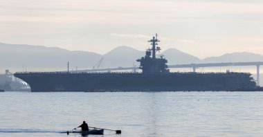 A man rows past the USS Abraham Lincoln as it deploys from San Diego Naval Air Station North Island in San Diego, California, U.S., Jan. 3, 2022. (Reuters File Photo)