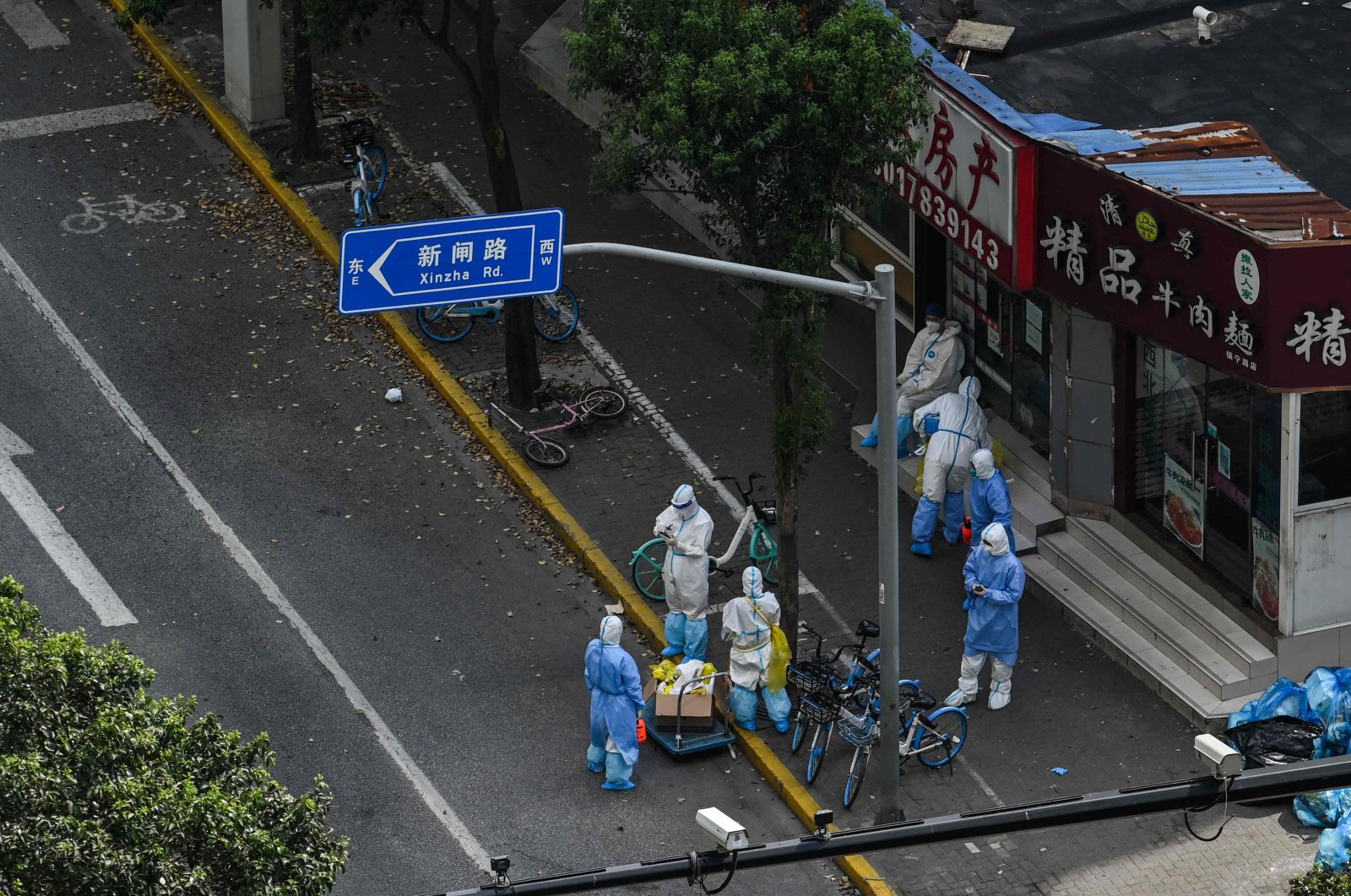 Health workers wearing personal protective equipment (PPE) stand next to the entrance of a neighborhood during a COVID-19 lockdown in the Jing&#039;an district in Shanghai on April 12, 2022. (AFP Photo)