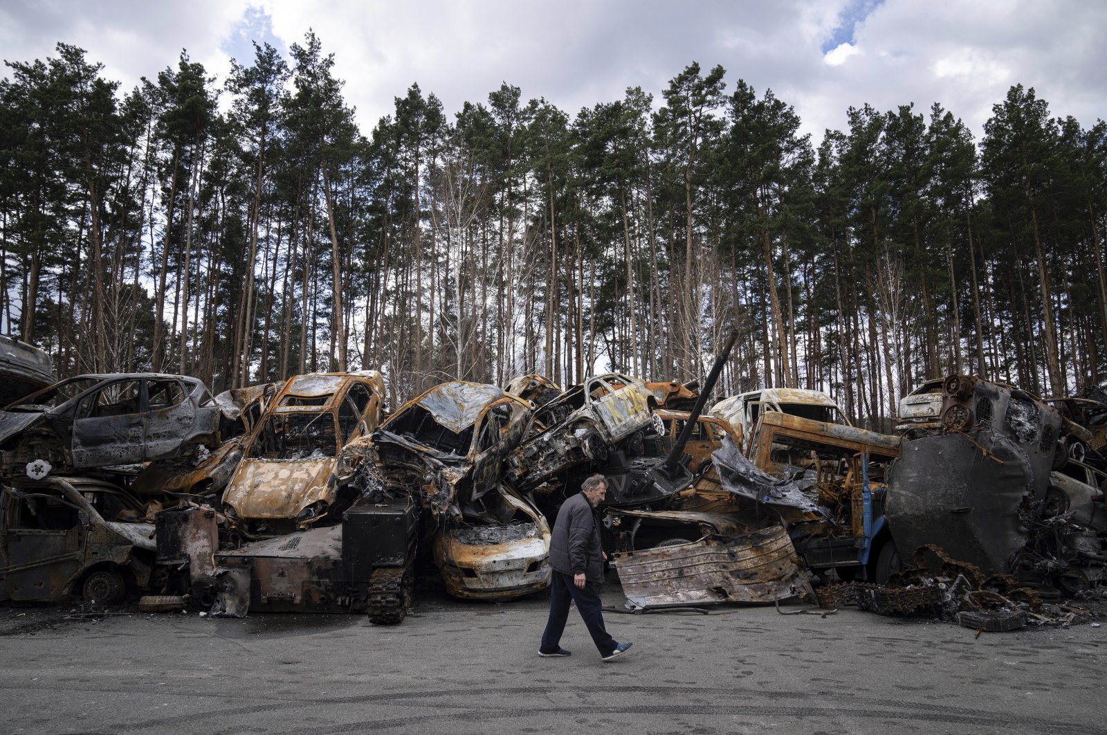 A man walks past a storage place for burned armed vehicles and cars, in the outskirts of Kyiv, Ukraine, April 11, 2022. (AP Photo)