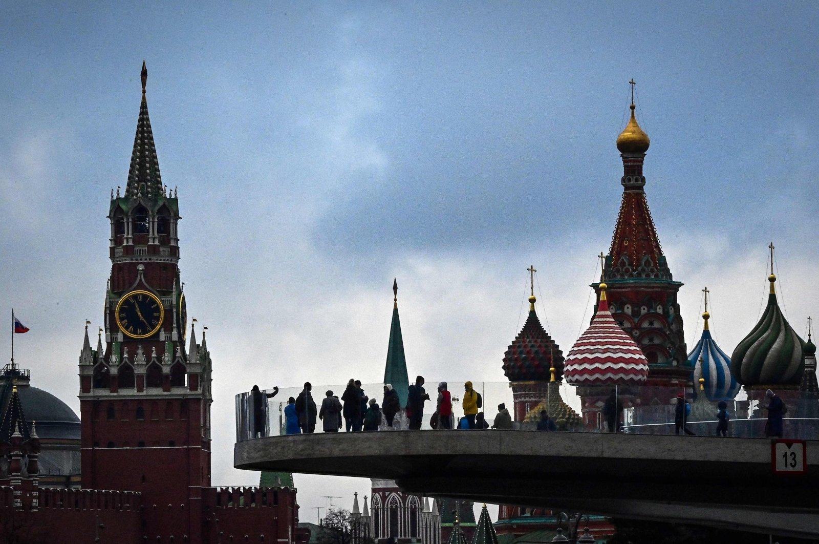 Pedestrians walk on a bridge in the Zaryadye Park, with the Kremlin&#039;s Spasskaya tower and St. Basil Cathedral in the background, Moscow, Russia, Nov. 4, 2021. (AFP Photo)