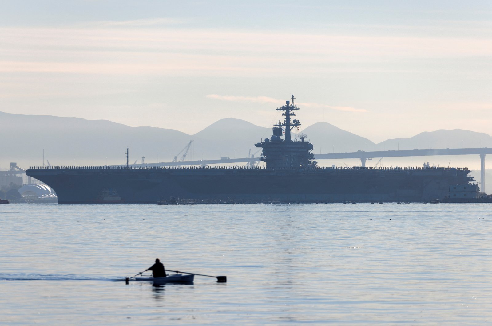 A man rows past the USS Abraham Lincoln as it deploys from San Diego Naval Air Station North Island in San Diego, California, U.S., Jan. 3, 2022. (Reuters File Photo)
