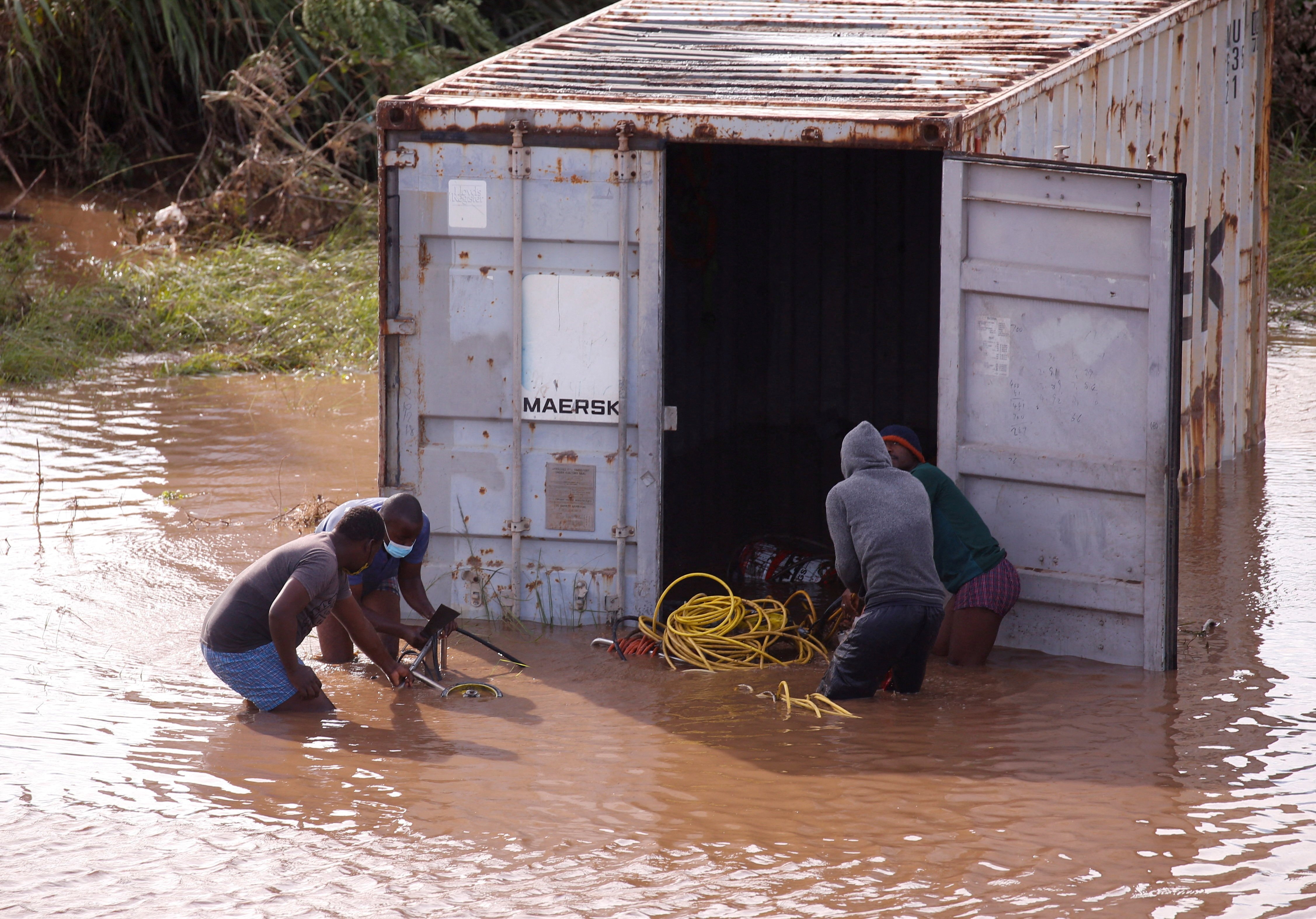 People loot a shipping container, which was washed away after heavy rains caused flooding in Durban, South Africa, April 12, 2022. (REUTERS PHOTO)