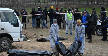 Journalists gather as bodies are exhumed and removed from a mass grave on the grounds of the St. Andrew and Pyervozvannoho All Saints Church in the Ukrainian town of Bucha, northwest of Kyiv, April 13, 2022. (AFP Photo)