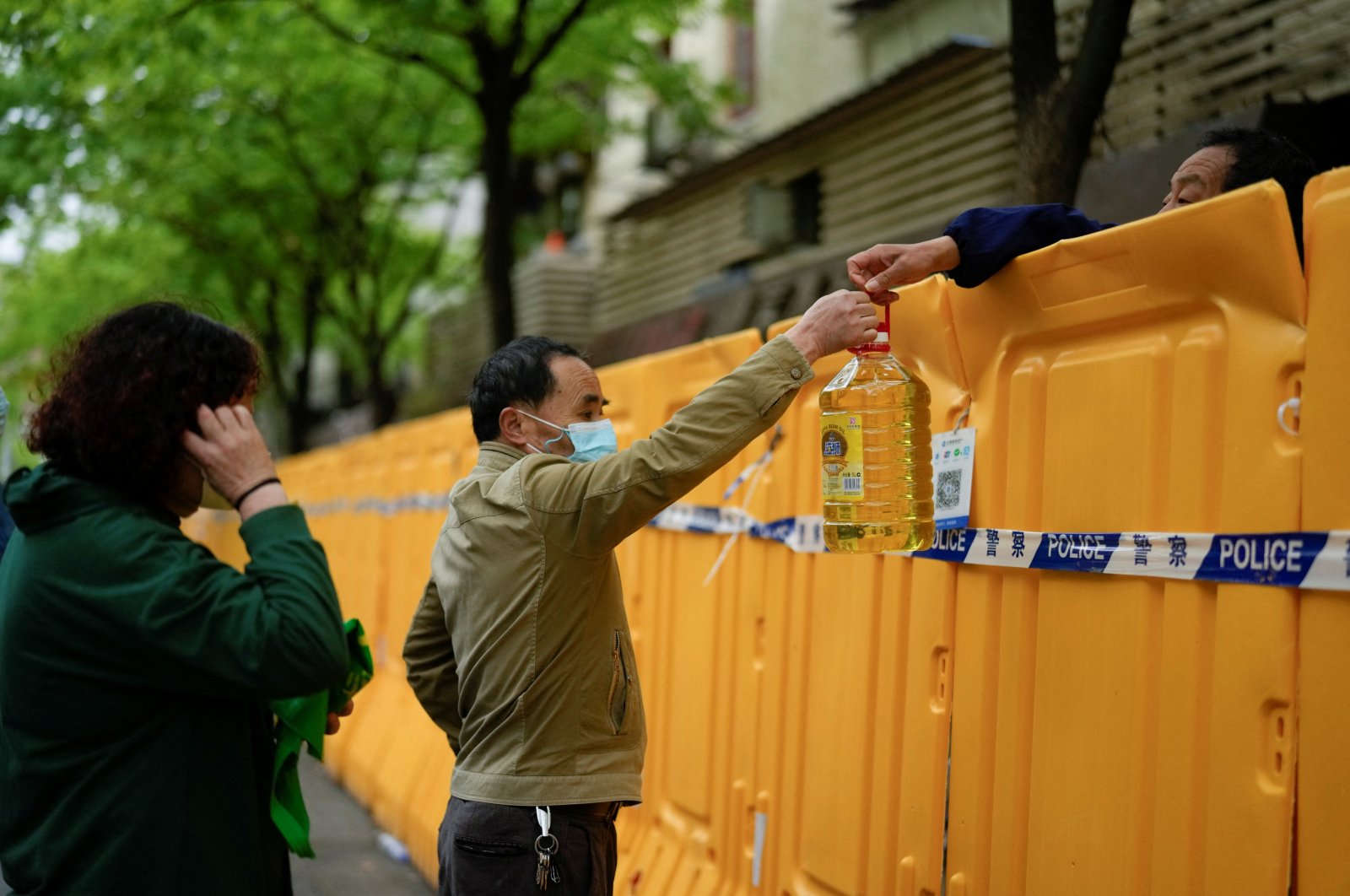 People pass edible oil over the barriers at a street market under lockdown amid COVID-19 pandemic, Shanghai, China, April 13, 2022. (REUTERS PHOTO)