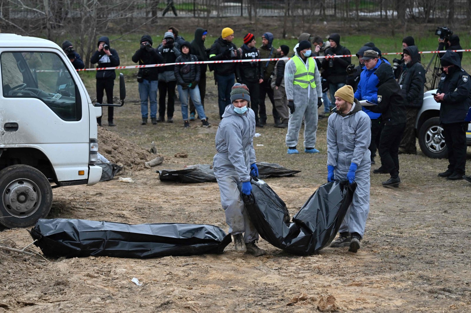 Journalists gather as bodies are exhumed and removed from a mass grave on the grounds of the St. Andrew and Pyervozvannoho All Saints Church in the Ukrainian town of Bucha, northwest of Kyiv, April 13, 2022. (AFP Photo)