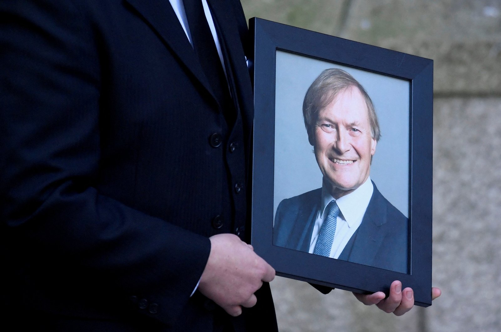 A portrait of British politician David Amess, who was stabbed to death during a meeting with constituents, is carried into Westminster Cathedral for a remembrance mass in his honor, London, Britain, Nov. 23, 2021. (REUTERS PHOTO)