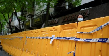 A woman looks over a barrier at an area under lockdown amid COVID-19 pandemic, Shanghai, China, April 13, 2022. (Reuters Photo)