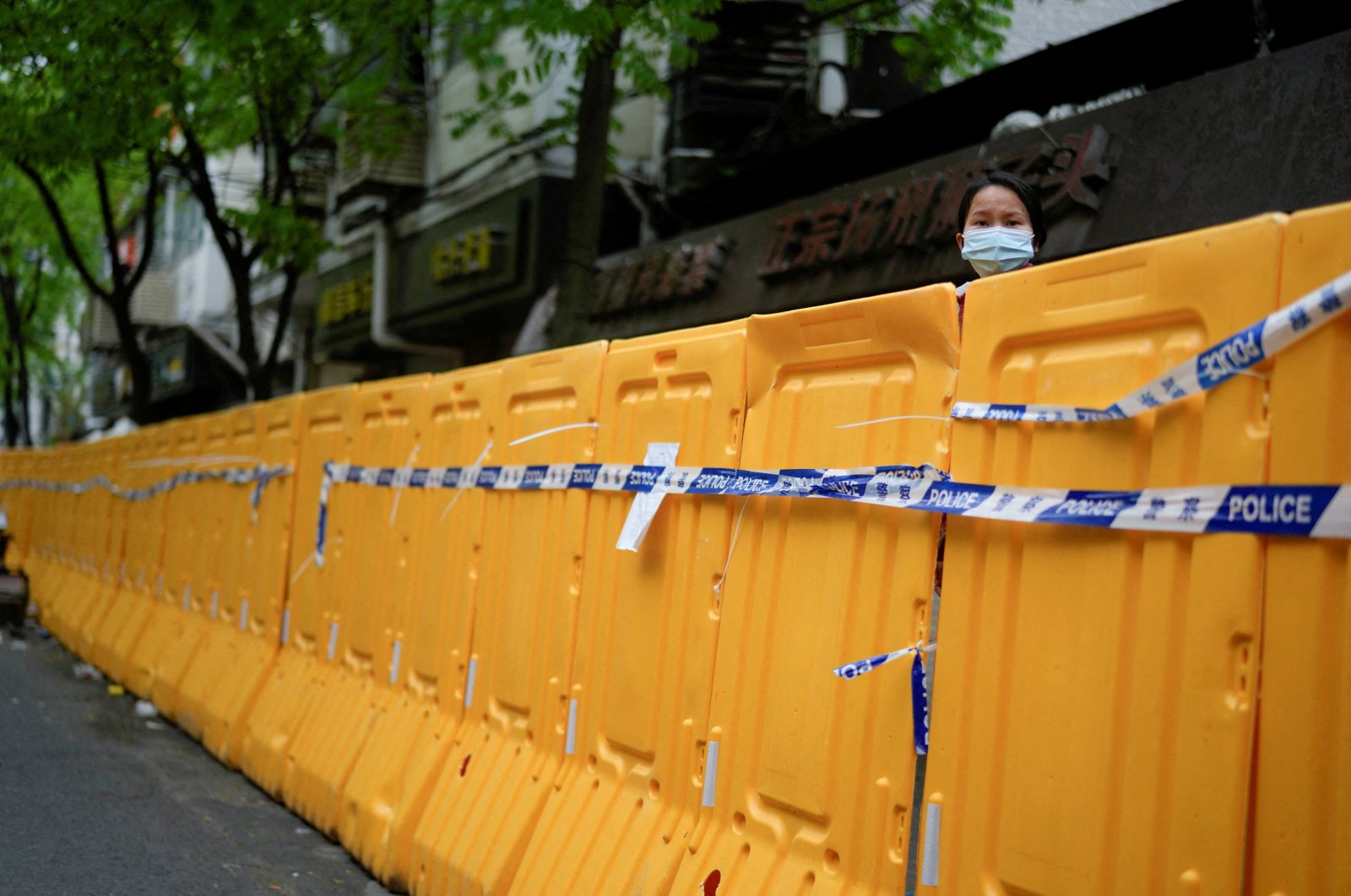 A woman looks over a barrier at an area under lockdown amid COVID-19 pandemic, Shanghai, China, April 13, 2022. (Reuters Photo)