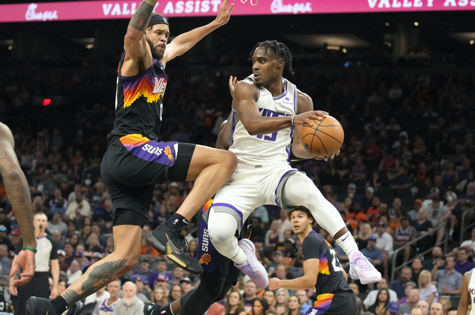 Kings guard Davion Mitchell (R) drives on Suns center JaVale McGee in an NBA game, Phoenix, U.S., April 10, 2022. (AP Photo)