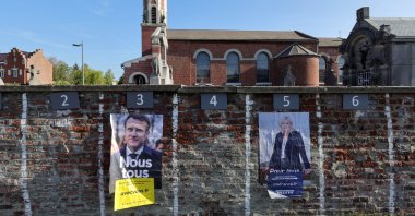 Official campaign posters of French presidential election candidates Marine le Pen, leader of French far-right National Rally (Rassemblement National) party, and French President Emmanuel Macron, candidate for his re-election, displayed on a cemetery wall in Aubencheul-au-Bac, France, April 16, 2022. (REUTERS)