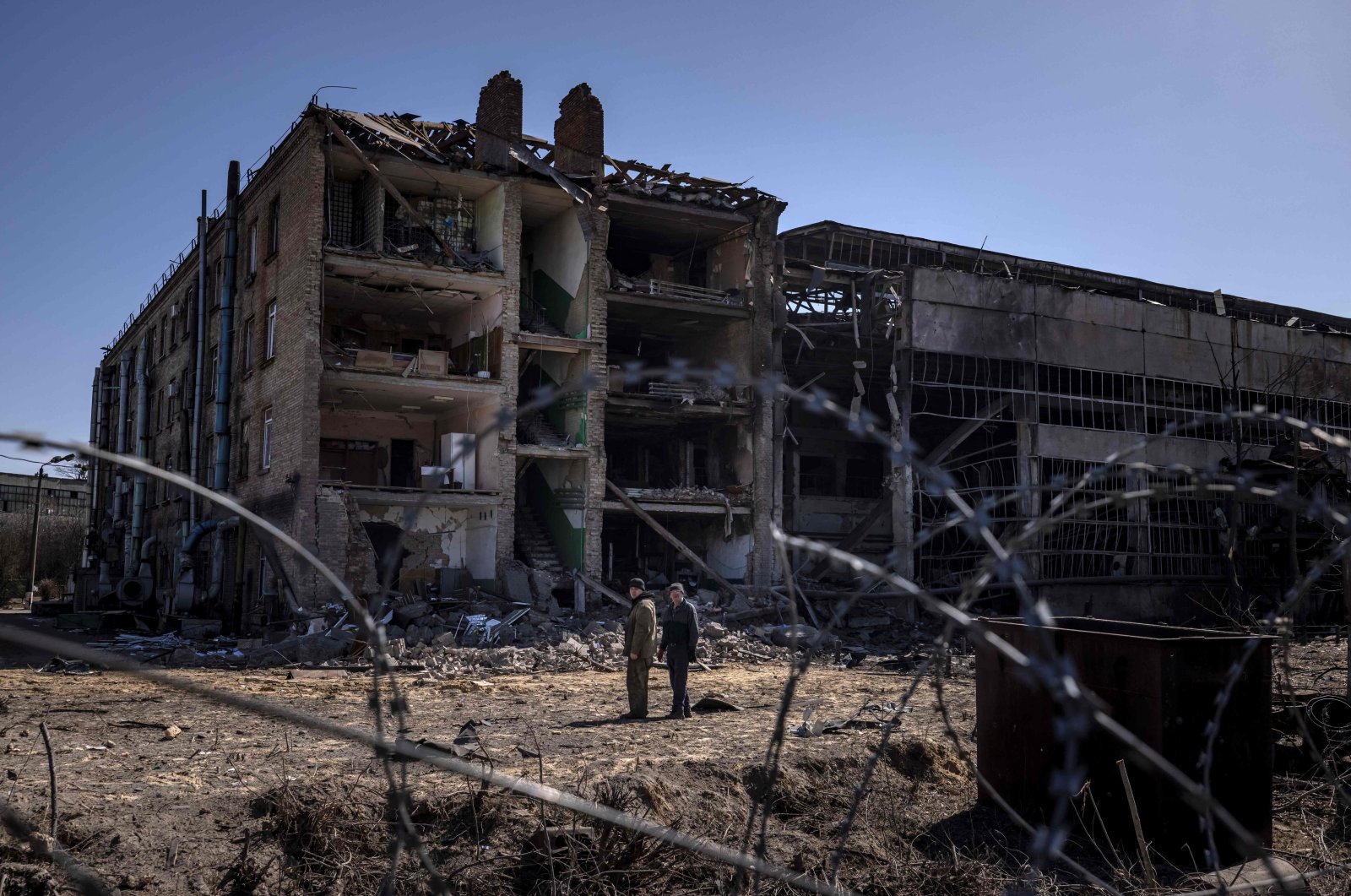 People stand beside damaged buildings at the Vizar company military-industrial complex, after the site was hit by overnight Russian strikes, in the town of Vyshneve, southwestern suburbs of Kyiv, Ukraine, April 15, 2022. (AFP Photo)