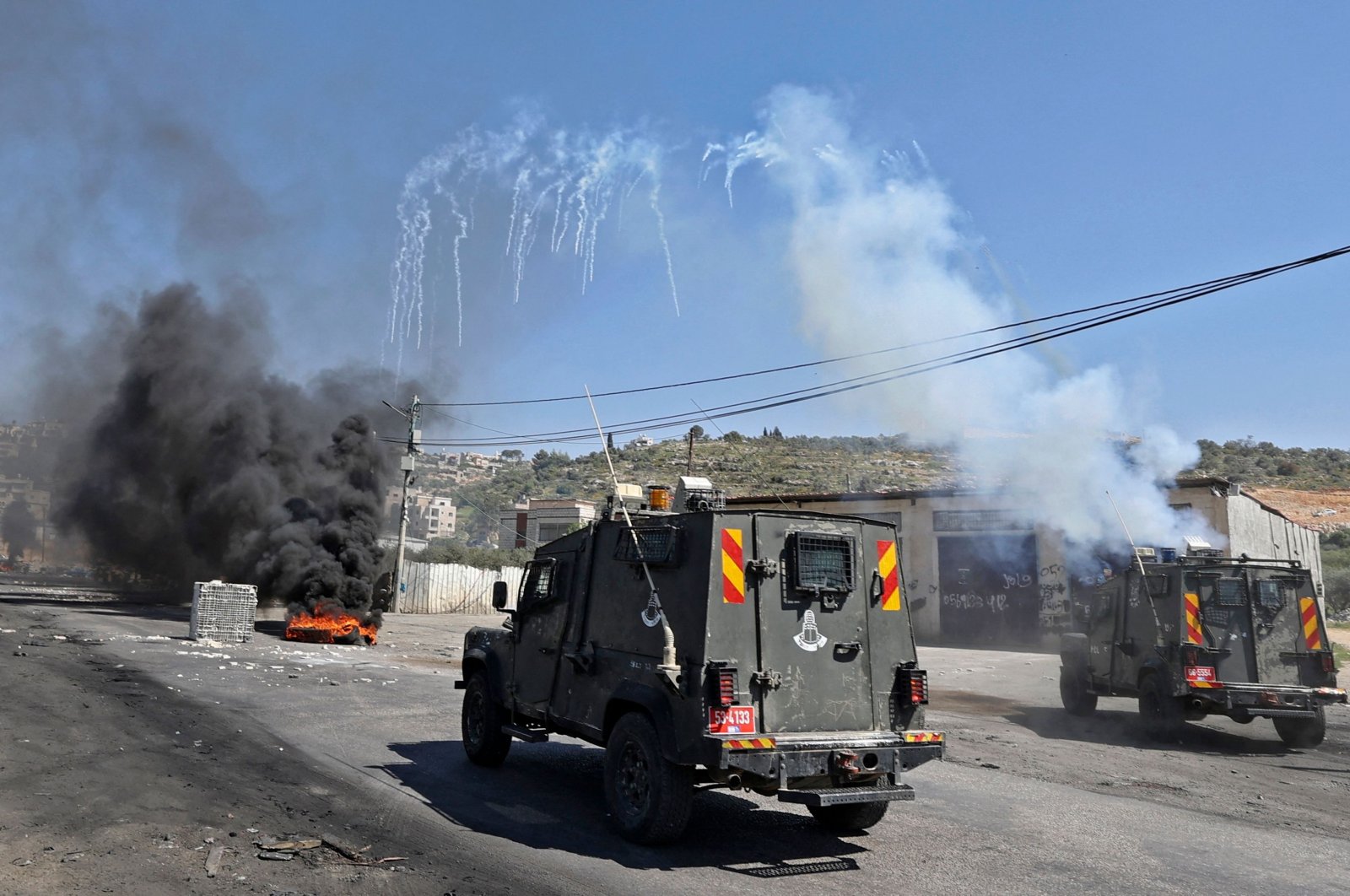 Israeli security members fire tear gas from vehicles amid clashes with Palestinian protesters during a demonstration against Jewish settlements and in support of Jerusalem's Al-Aqsa mosque, on the main street of Beita village in the occupied West Bank, on April 15, 2022. (AFP Photo)
