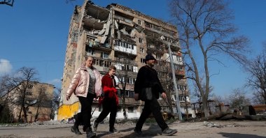 Local residents walk past an apartment building damaged during the Ukraine-Russia conflict in the southern port city of Mariupol, Ukraine, April 15, 2022. (Reuters Photo)