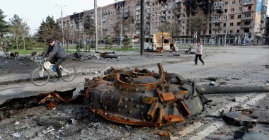 People walk past the turret of a tank, which was destroyed during Ukraine-Russia conflict in the southern port city of Mariupol, Ukraine, April 17, 2022. (Reuters Photo)