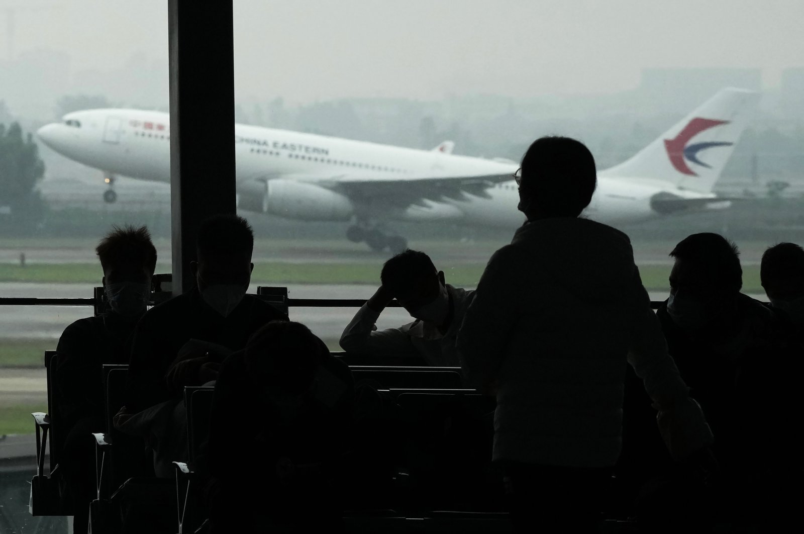 Passengers wait for their flight as a China Eastern flight takes off from the runway of Baiyun Airport on March 25, 2022, in southern Guangzhou province, China. (AP Photo)