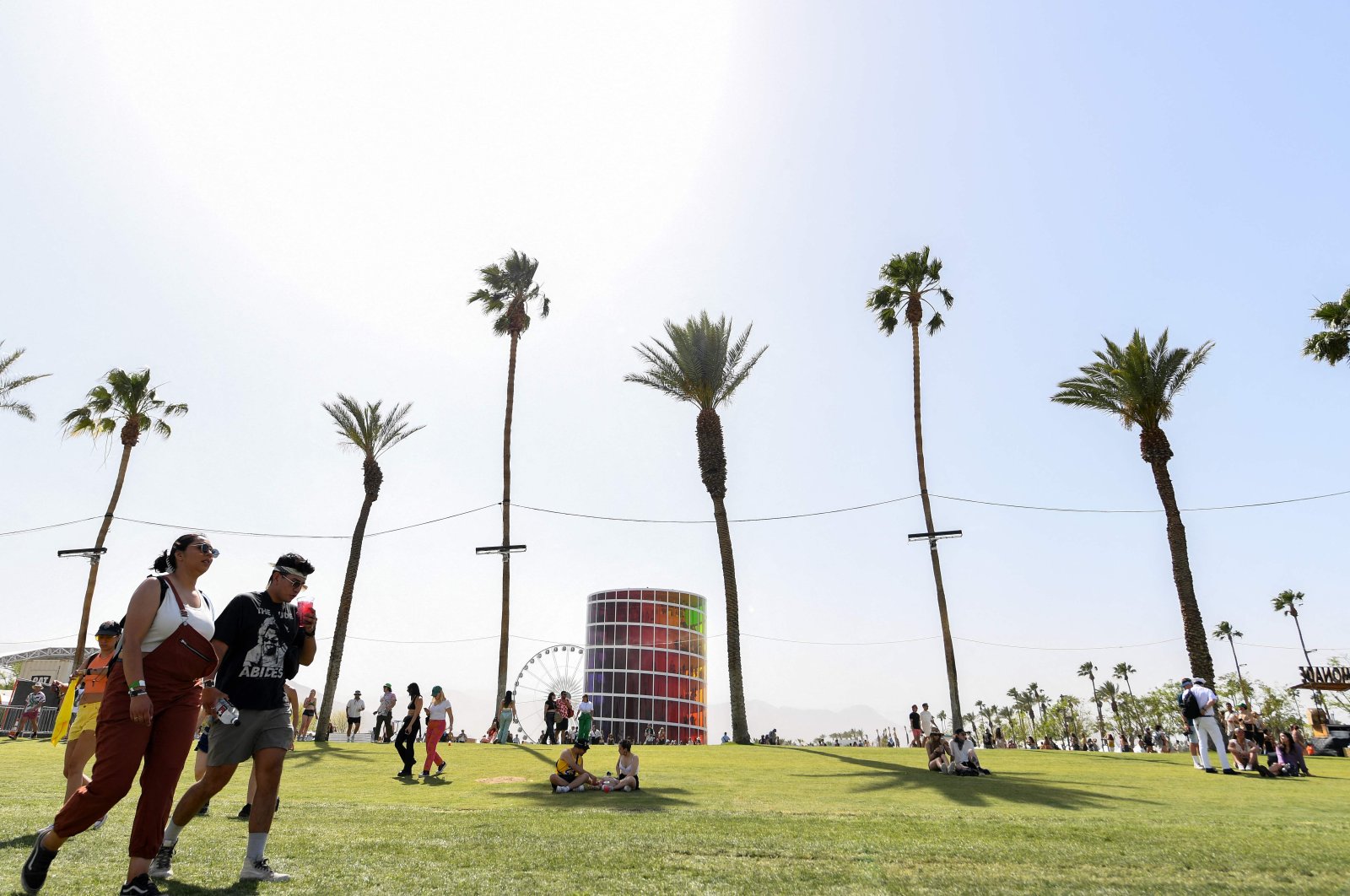 People sit in the shade of palm trees at the Coachella Valley Music and Arts Festival in Indio, California, April 16, 2022. (AFP Photo)