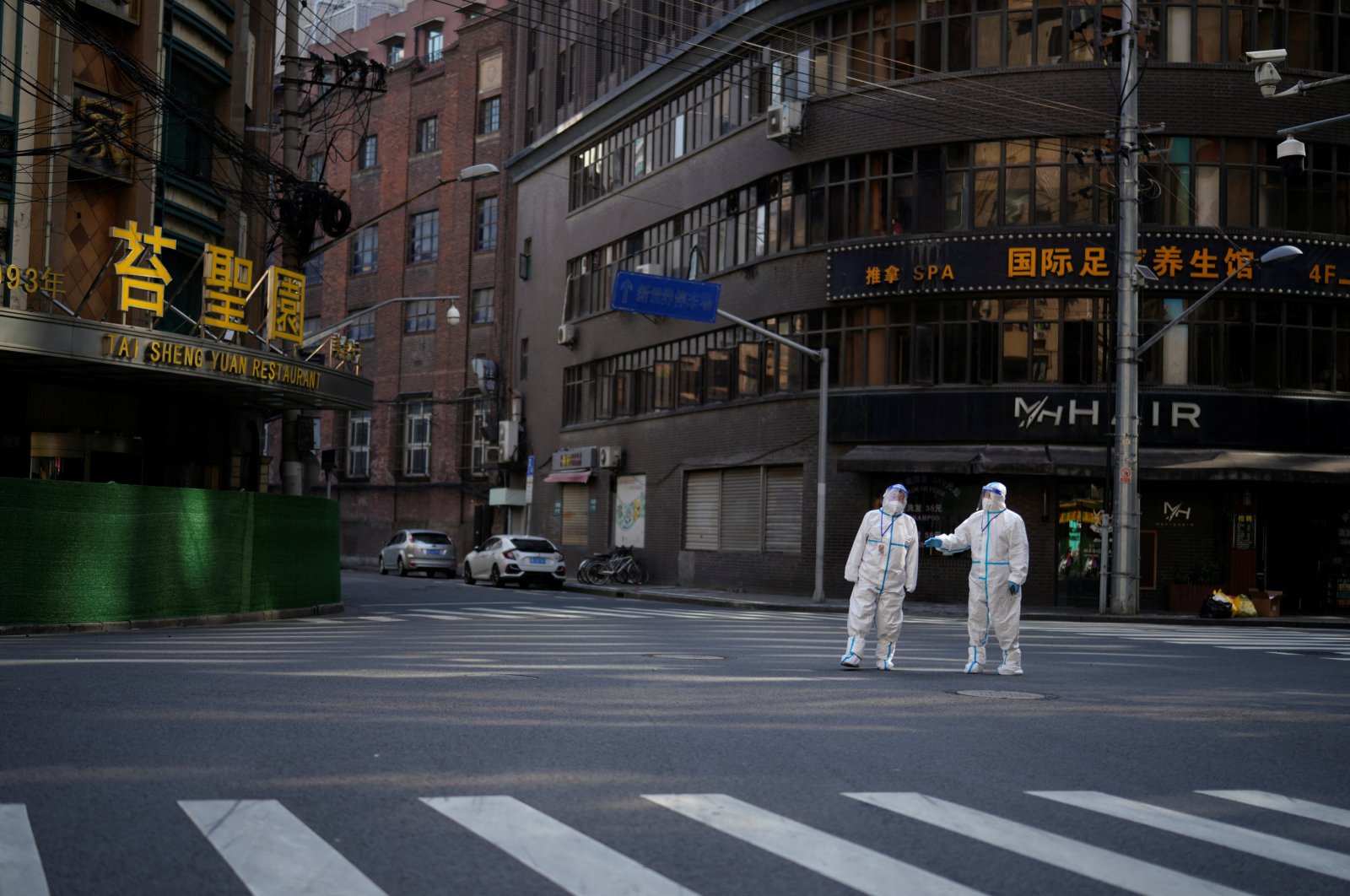 Workers in protective suits stand on a street during a lockdown, amid the COVID-19 pandemic, Shanghai, China, April 16, 2022. (Reuters Photo)