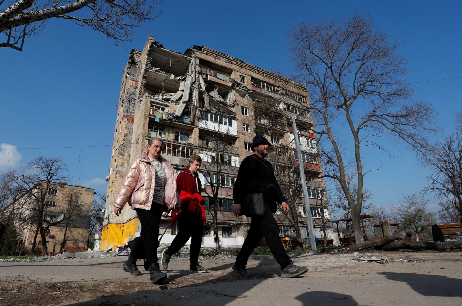 Local residents walk past an apartment building damaged during the Ukraine-Russia conflict in the southern port city of Mariupol, Ukraine, April 15, 2022. (Reuters Photo)