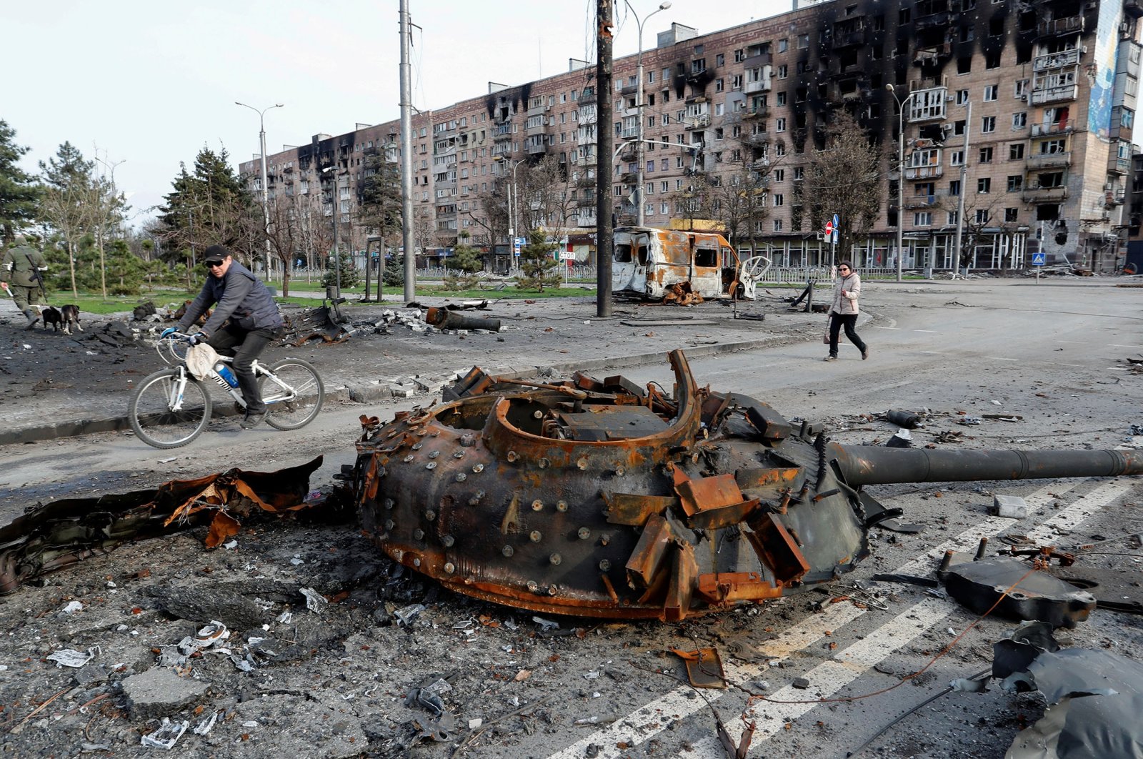 People walk past the turret of a tank, which was destroyed during Ukraine-Russia conflict in the southern port city of Mariupol, Ukraine, April 17, 2022. (Reuters Photo)