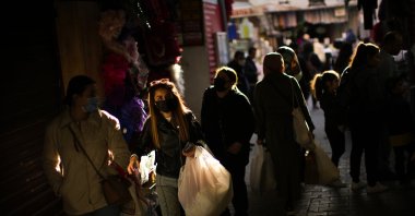 People wearing protective masks carry shopping bags in a commercial street in Istanbul, Turkey, April 14, 2022. (AP PHOTO)