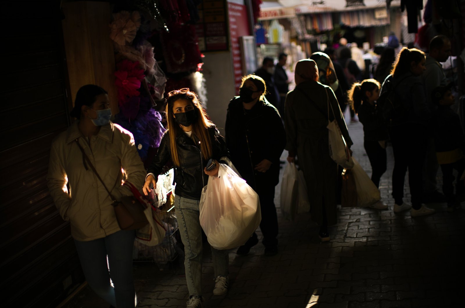 People wearing protective masks carry shopping bags in a commercial street in Istanbul, Turkey, April 14, 2022. (AP PHOTO)