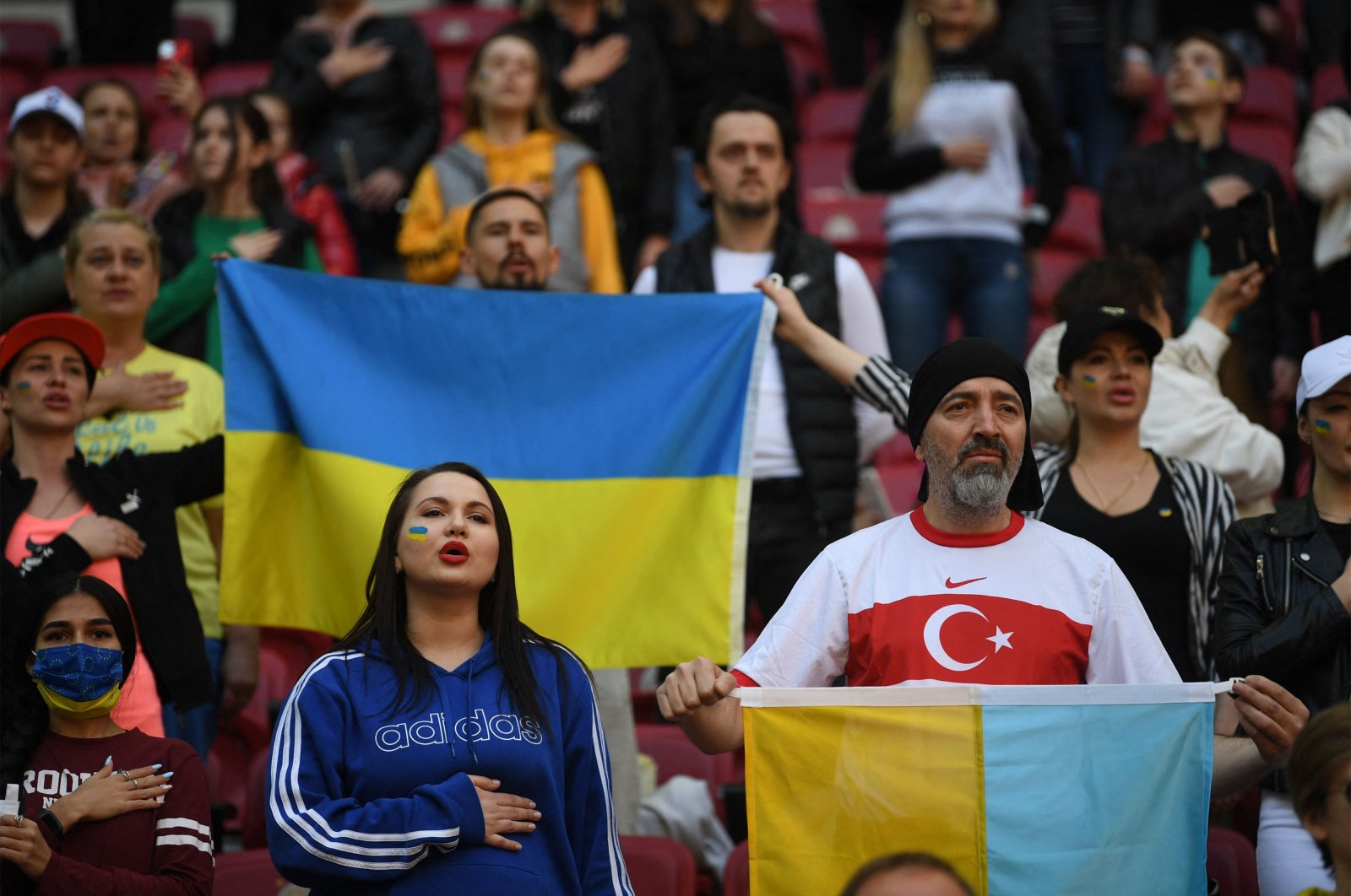Supporters listen to national anthems with flags of Ukraine during the ceremony before a friendly charity football match between Galatasaray and Dinamo Kyiv held for peace and to raise money for Ukrainian refugees, at the NEF Stadium in Istanbul, on April 14, 2022. (AFP Photo)