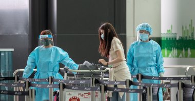 A woman waits for a shuttle bus to her quarantine hotel after landing at Hong Kong International airport in Hong Kong, China, March 21, 2022. (EPA Photo)