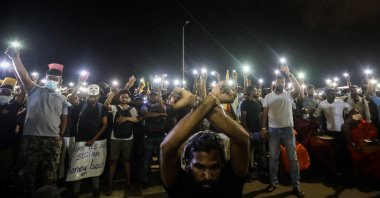 Protesters light their mobile phones’ flashlights in memory of the protester killed in a police shooting during the clash in Rambukkana, in front of the Presidential Secretariat in Colombo, Sri Lanka, April 19, 2022. (EPA Photo)