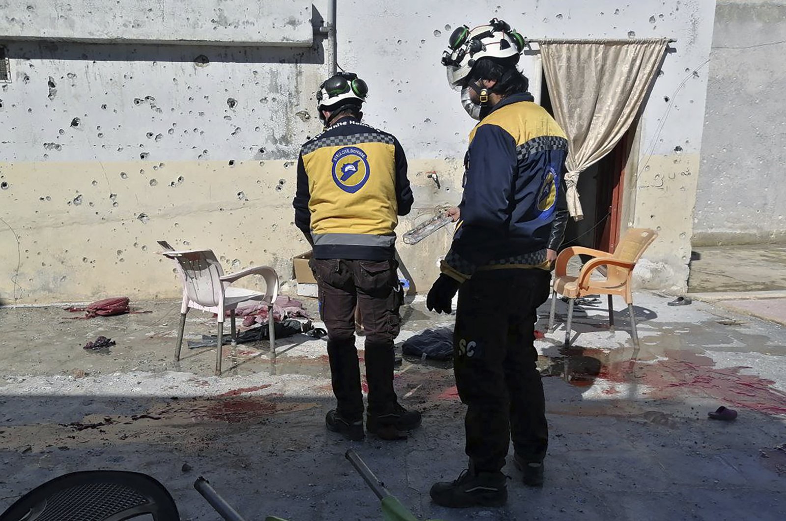 In this photo provided by the Syrian Civil Defense White Helmets, which has been authenticated based on its contents and other AP reporting, Syrian White Helmet civil defense workers stand at the site where a shell struck in the Maaret al-Naasan village in Idlib province, Syria, Saturday, Feb. 12, 2022. (Syrian Civil Defense White Helmets via AP)
