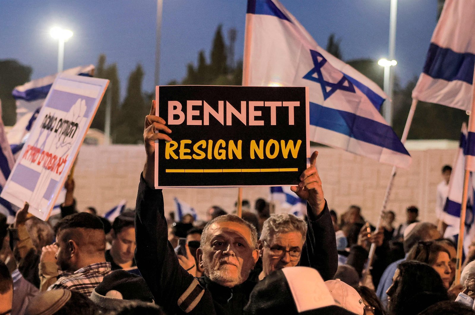 A man holds up a sign reading in English &quot;(Israeli Prime Minister Naftali) Bennett resign now&quot; during an anti-government protest by Israeli right-wing supporters in Jerusalem, April 6, 2022. (AFP Photo)