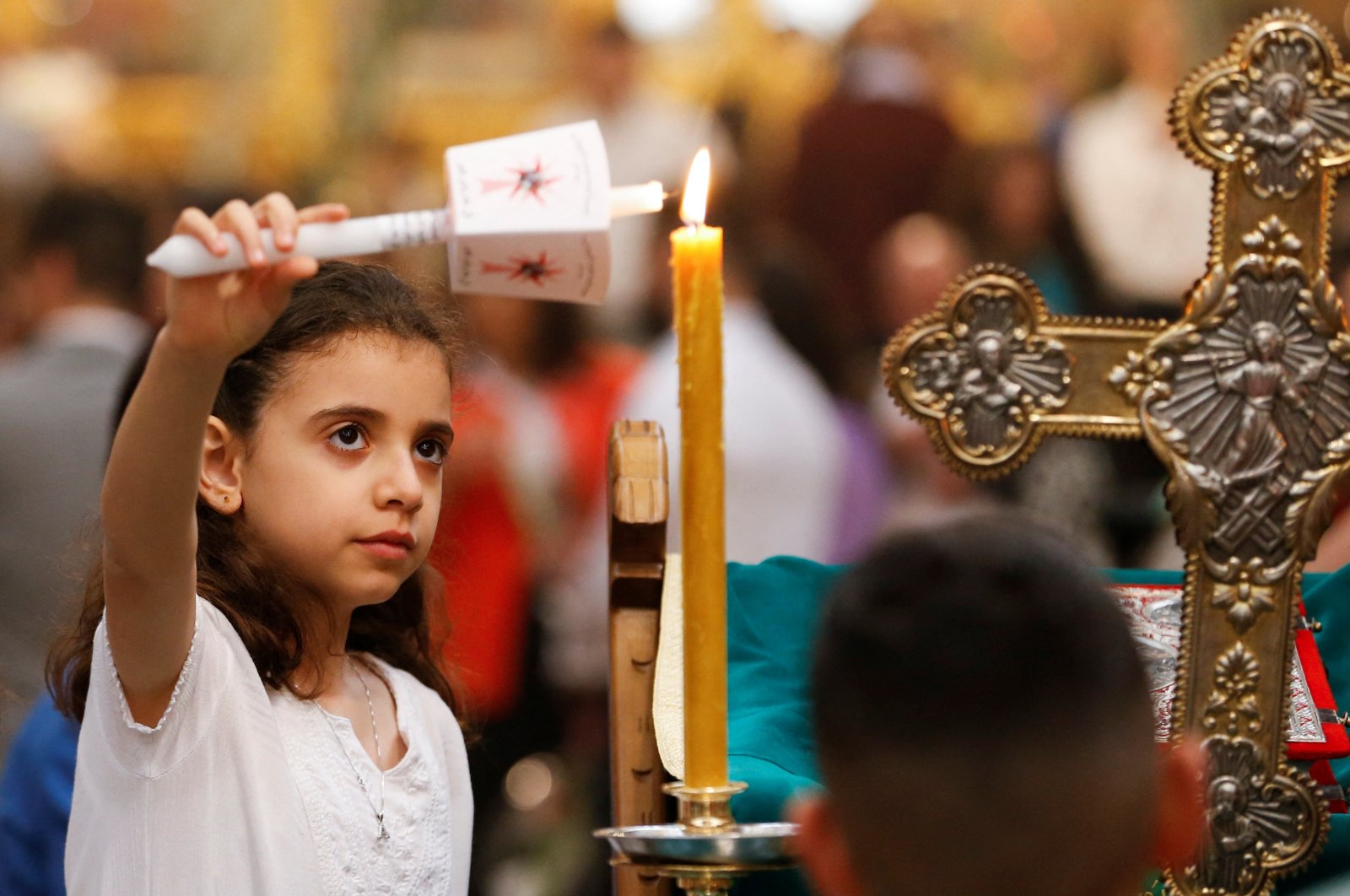 A Palestinian girl lights a candle during Palm Sunday at the Church of the Nativity, in Bethlehem in the Israeli-occupied West Bank, Palestine, April 17, 2022. (Reuters Photo)