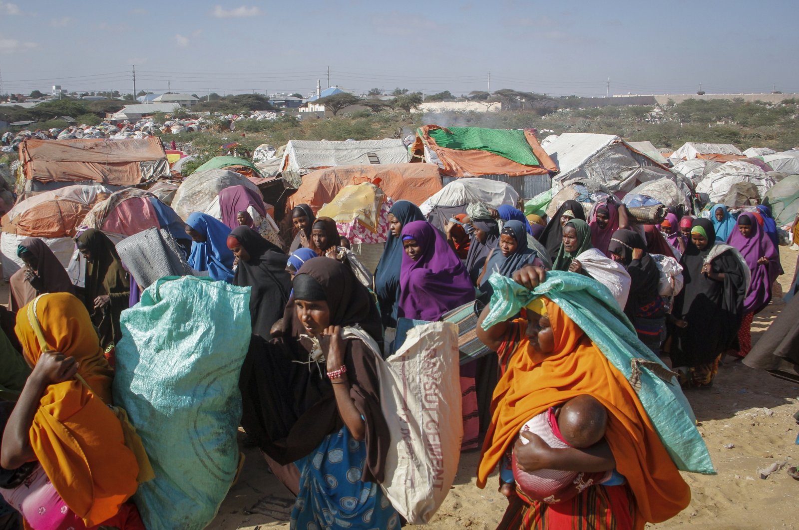 Somalis who fled drought-stricken areas carry their belongings as they arrive at a makeshift camp on the outskirts of the capital Mogadishu, Somalia, Feb. 4, 2022. (AP Photo)