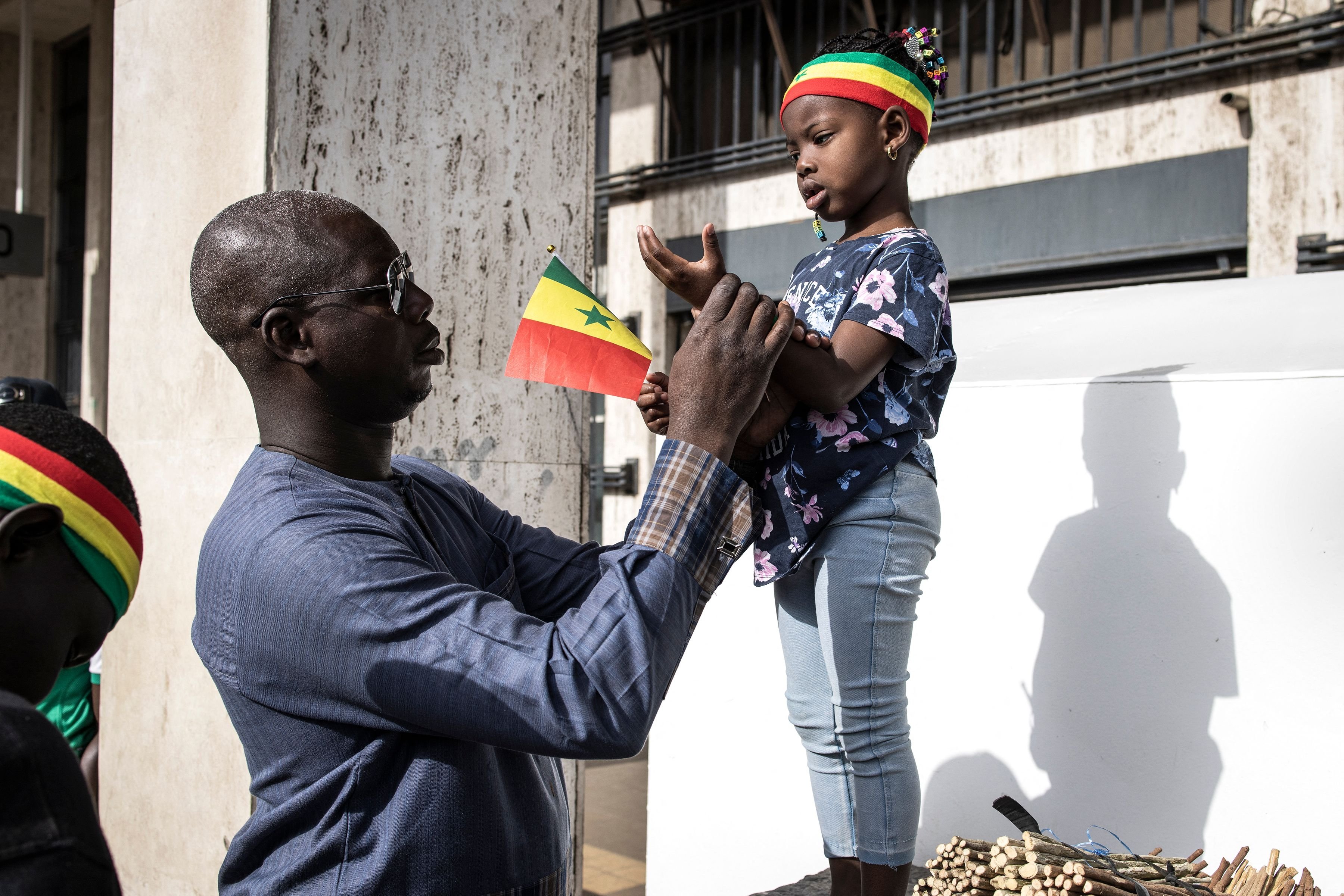 A man dresses his daughter up in the colors of the Senegalese national flag during celebrations for Independence Day in Dakar, April 4, 2022. (Photo via AFP)