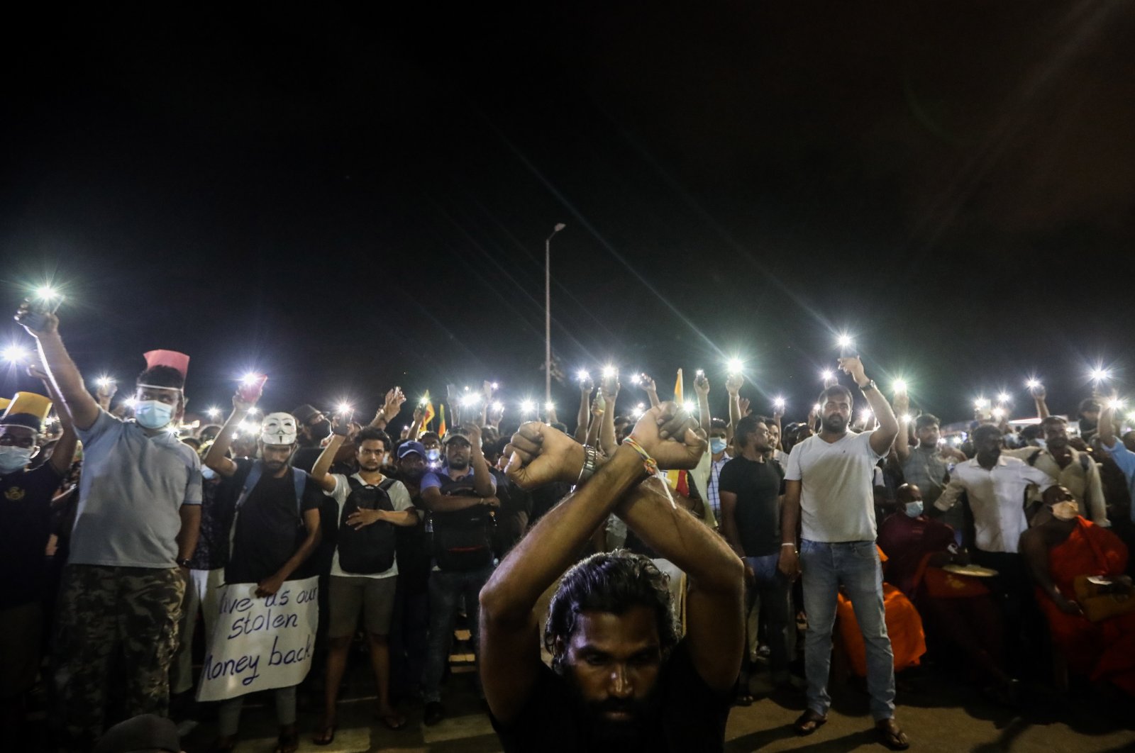 Protesters light their mobile phones’ flashlights in memory of the protester killed in a police shooting during the clash in Rambukkana, in front of the Presidential Secretariat in Colombo, Sri Lanka, April 19, 2022. (EPA Photo)