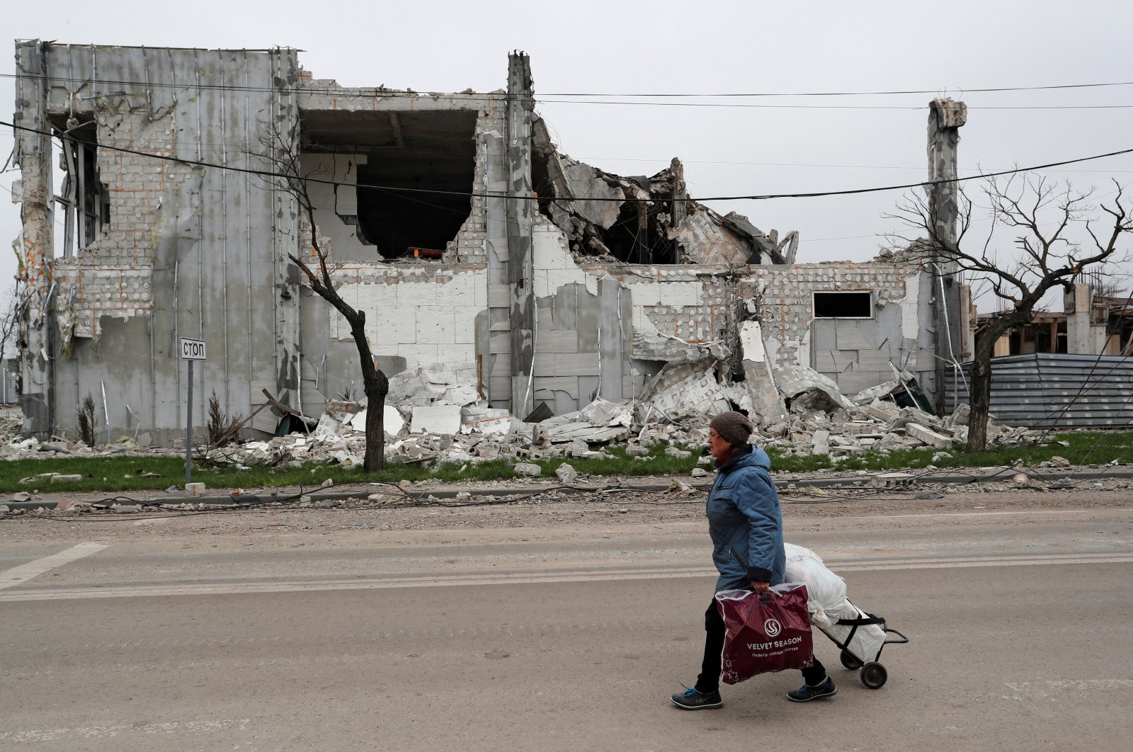 A local resident walks past a building destroyed during the Ukraine-Russia conflict in the southern port city of Mariupol, Ukraine April 19, 2022. REUTERS/Alexander Ermochenko/File Photo