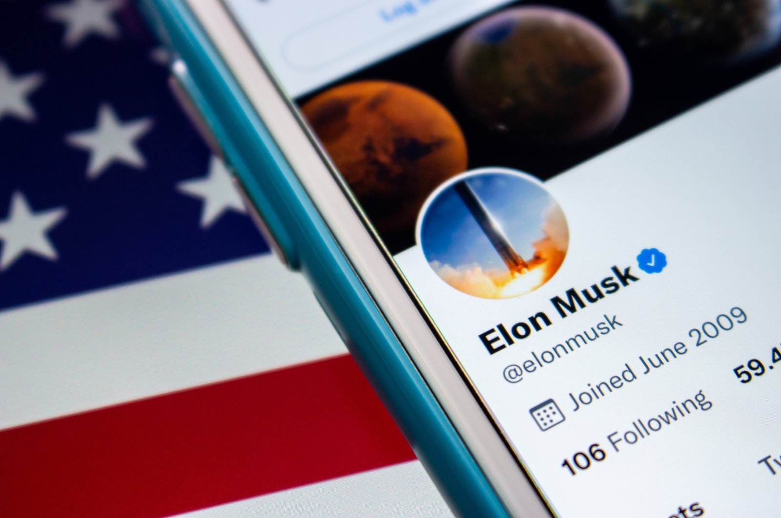 The Twitter account of Elon Musk is seen with the U.S. flag in the background. (Photo by Shutterstock)