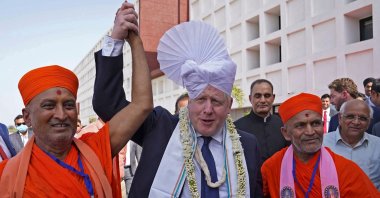 Britain&#039;s Prime Minister Boris Johnson (C) gets a traditional turban tied on his head upon his arrival at the Gujarat Biotechnology University in Gandhinagar on April 21, 2022. (AFP Photo)
