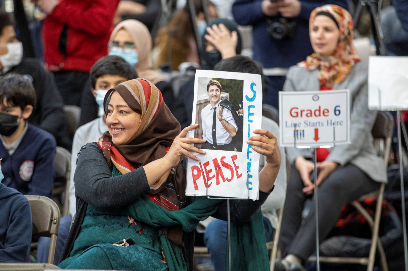 A woman waits with a sign for Canadian Prime Minister Justin Trudeau as he meets members of the Muslim community during a visit to the International School of Cambridge, Ontario, Canada, April 20, 2022. (Reuters Photo)