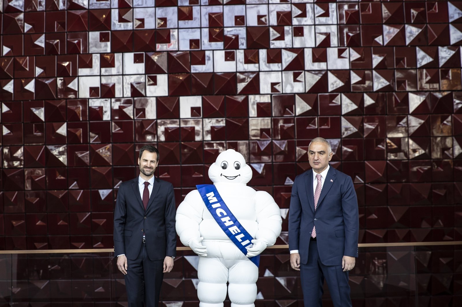 Gwendal Poullennec (L), International Director of Michelin Guides, and Mehmet Nuri Ersoy (R), Minister of Culture and Tourism, pose for a photo together with the Michelin mascot, in Istanbul, Turkey, April 21, 2022. (AA Photo)
