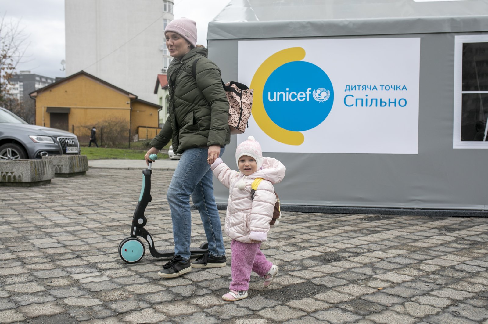 A woman walks with a small girl outside a UNICEF office. Manuel Fontaine, UNICEF director for emergency operations, and Afshan Khan, UNICEF regional director for Europe and Central Asia, together with Murat Sahin, UNICEF Representative in Ukraine, visited the Spilno center, Lviv, Ukraine, March 31, 2022. (Photo courtesy of UNICEF Turkey)