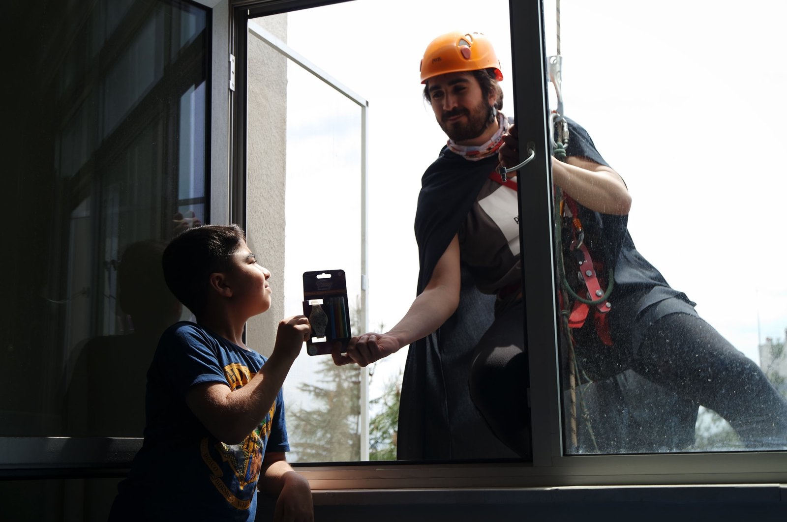 A college student dressed as a superhero gives a child a gift at his window at Uludağ University Hospital, in Bursa, Turkey, April 21, 2022. (AA Photo)