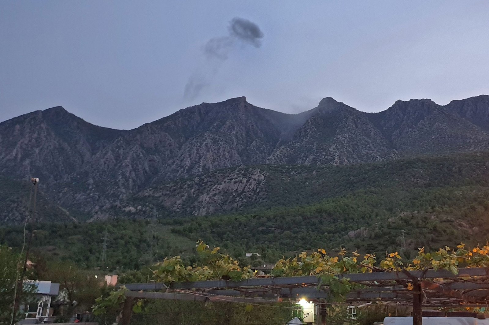 A picture taken on April 19, 2022, shows smoke billowing from behind the mountains of Matin (Jabal Matin) following a Turkish operation targeting PKK terrorists in northern Iraq. (AFP Photo)
