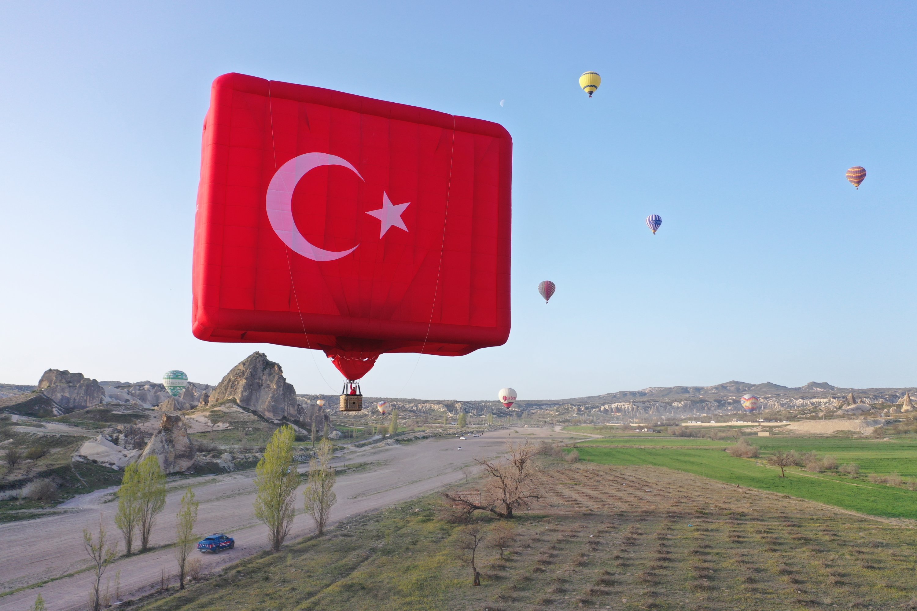 Turkish flag shaped hot air balloons dot the sky in Cappadocia