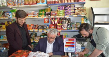 Ibrahim Kayaoğlu (C) calculates the debt he will pay on behalf of others at a grocery store, in Elazığ, eastern Turkey, April 24, 2022. (DHA PHOTO)