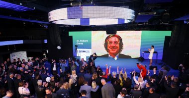 Leader of Gibanje Svoboda (Freedom Movement) Robert Golob appears on screen at the party base as people cheer while waiting for the results of the parliamentary election in Ljubljana, Slovenia April 24, 2022. (Reuters Photo)