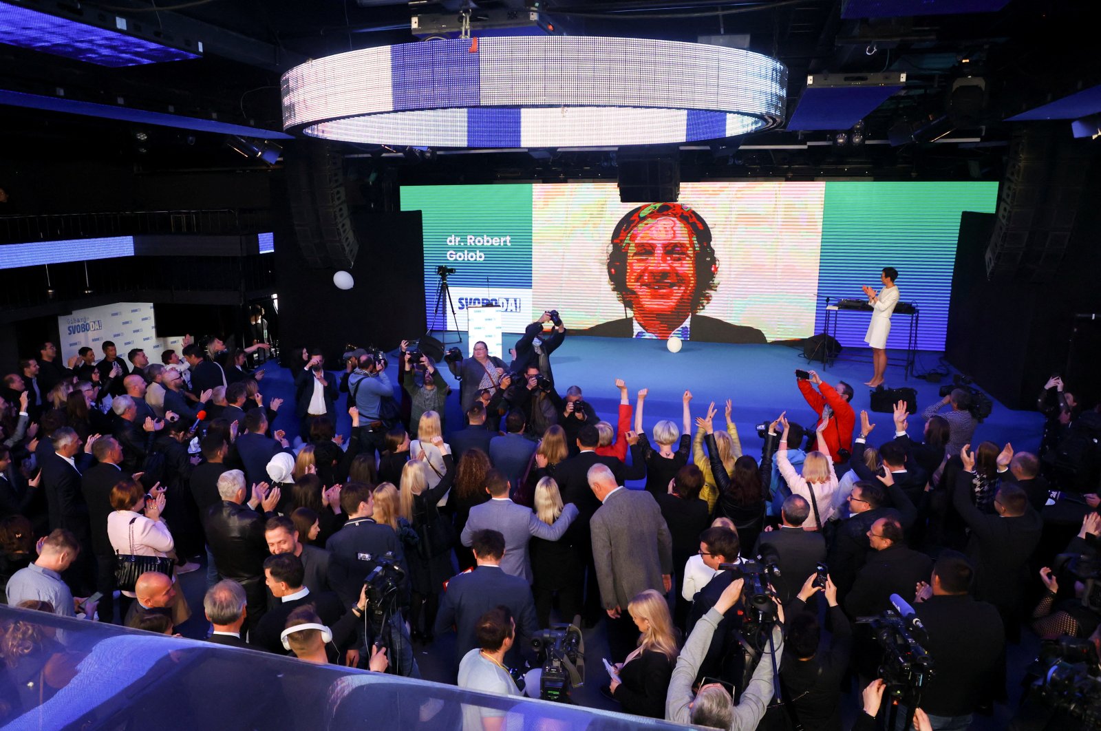Leader of Gibanje Svoboda (Freedom Movement) Robert Golob appears on screen at the party base as people cheer while waiting for the results of the parliamentary election in Ljubljana, Slovenia April 24, 2022. (Reuters Photo)