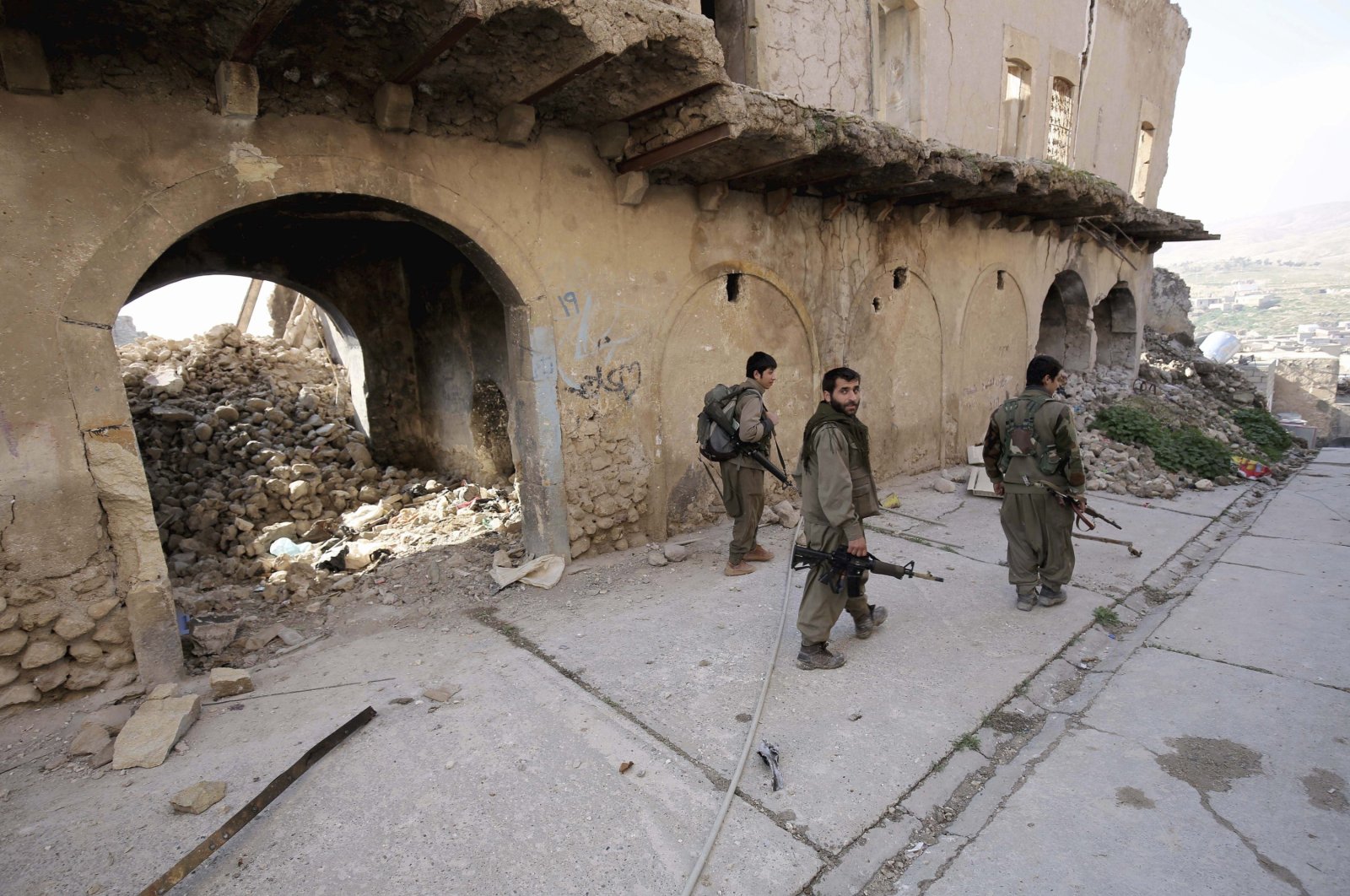 PKK terrorists walk in the damaged streets of Sinjar, Iraq, Jan. 29, 2015. (AP Photo)